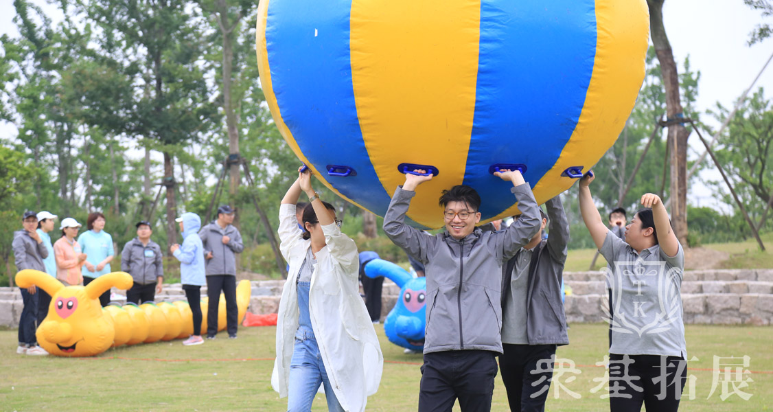 运转乾坤三夫拓展是一种趣味团队运动项目，此团建活动是团队成员举起充气大气球齐力向终点跑去，途中气球不可落地。速度最快的团队获胜。